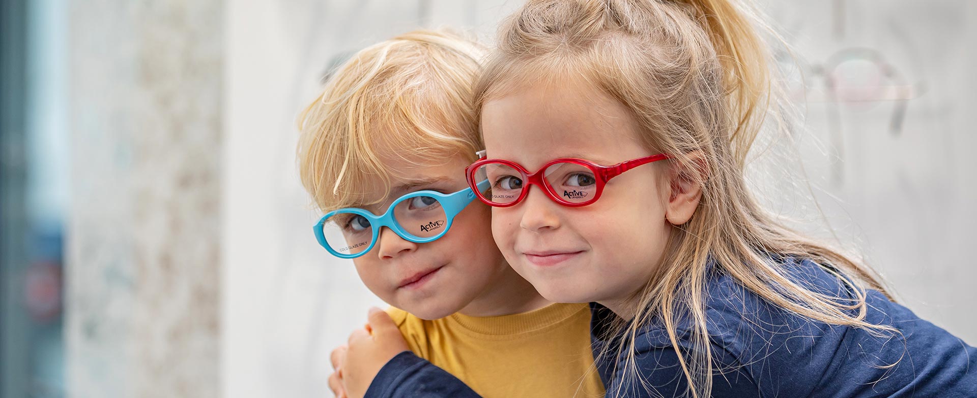 Zwei Kinder probieren sporttaugliche, hautfreundliche und elastische Kinderbrillen aus.