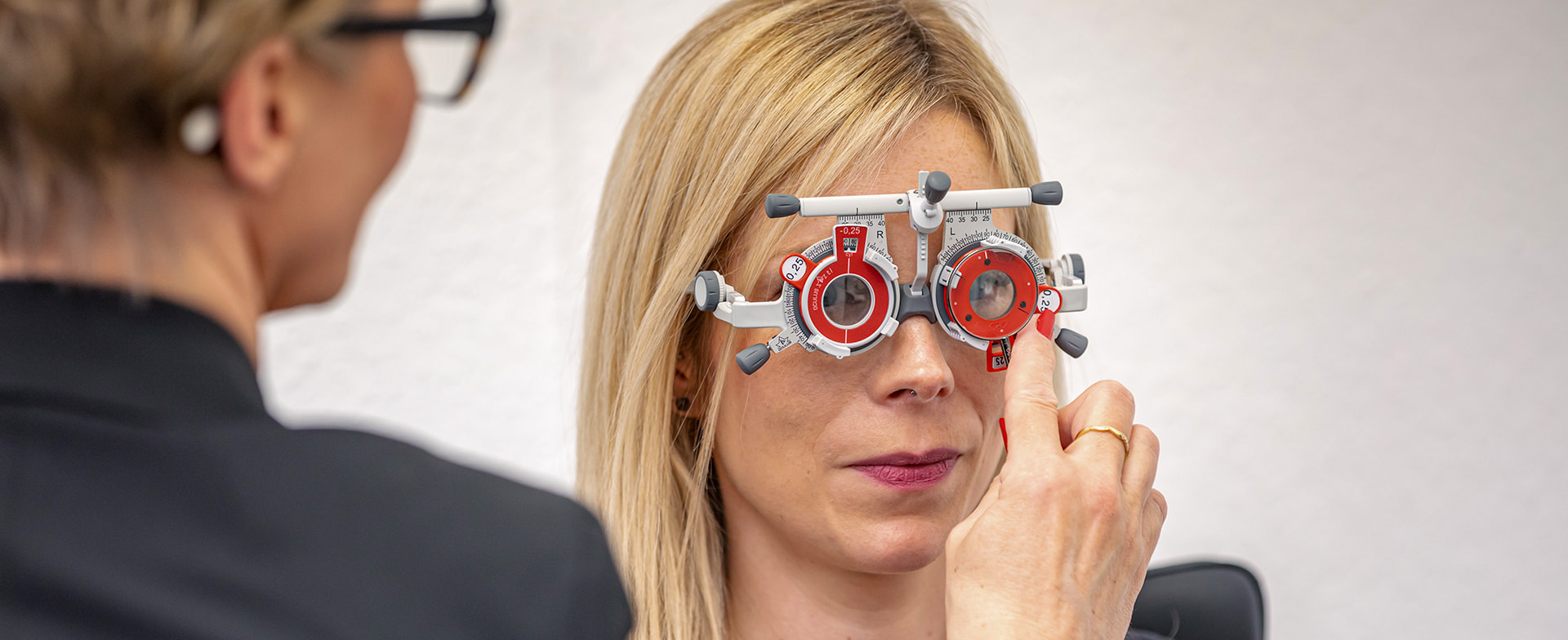 Staatlich geprüfte Augenoptikermeisterin bei der Arbeit: Hier führt sie mit einer Kundin eine präzise Refraktion und Sehanalyse durch, unterstützt durch eine Messbrille und passende Messgläser.